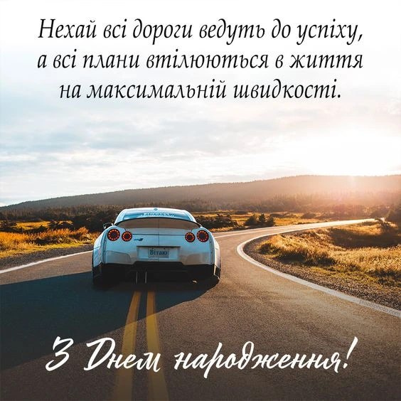 Білий спорткар на дорозі з привітанням з днем народження українською.