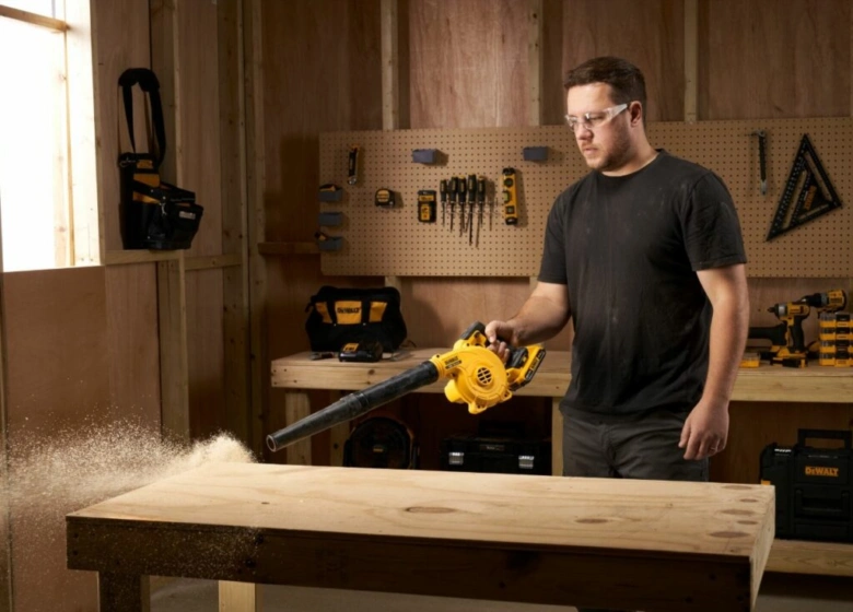 Чоловік використовує акумуляторний повітродувка DeWALT у майстерні.