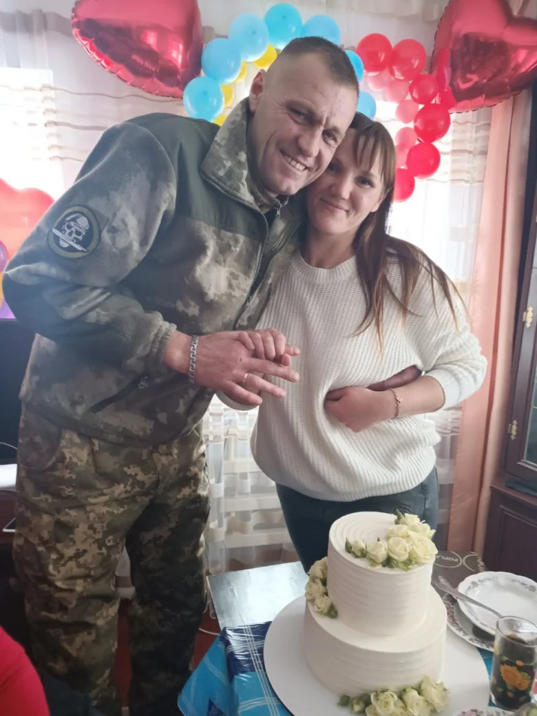 Чоловік у військовій формі та жінка з тортам на фоні кульок