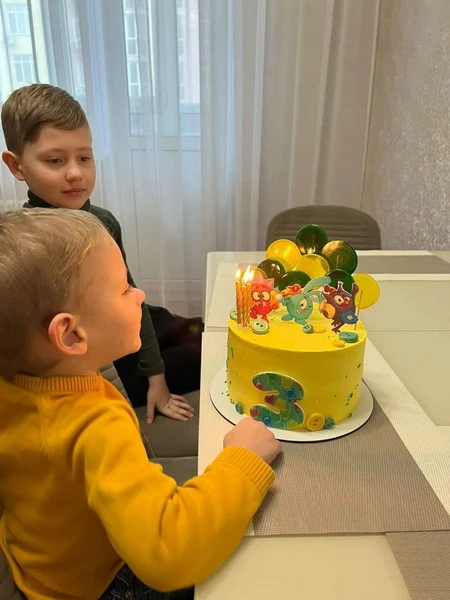 Два хлопчики дивляться на торт з днем народження.