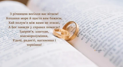 Два золоті обручальні кільця на відкритій книзі з привітанням.